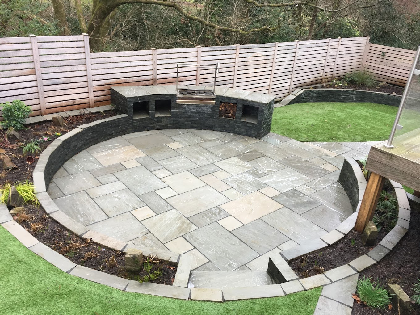New circular sandstone patio with slate seating wall and BBQ